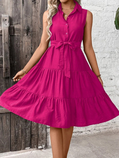 Woman wearing a bright pink dress against a rustic wooden and white brick wall.