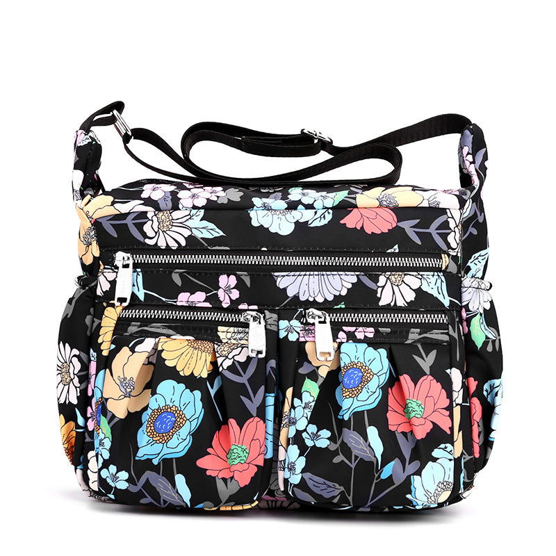 Floral crossbody bag with adjustable strap, zip front panel, and two utility pockets