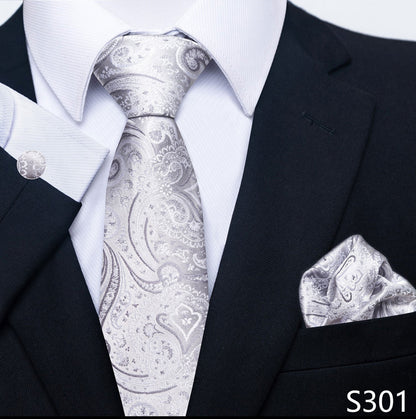 Black suit with white shirt, silver paisley tie, and matching pocket square on a white background.