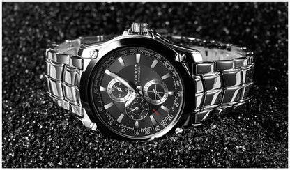 Silver watch with a black face on a dark textured background