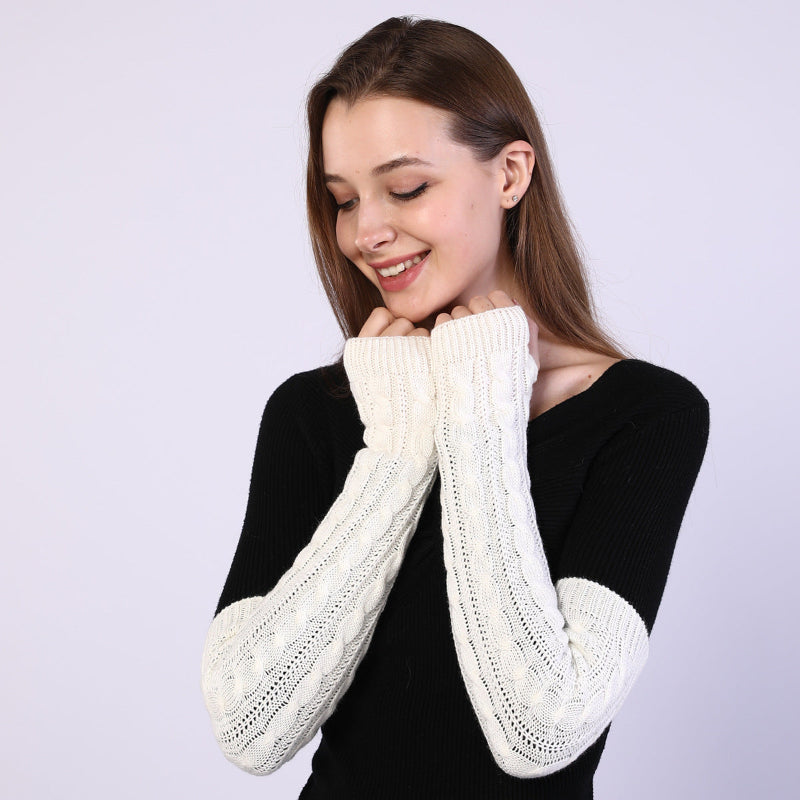 Woman wearing white knitted arm warmers against a light purple background