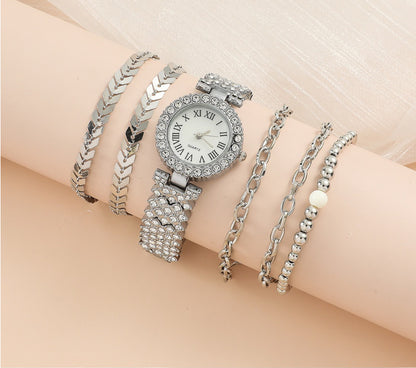 Silver watch and bracelets on a wrist against a beige background