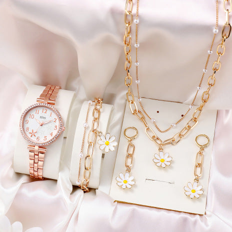 Rose gold watch and jewelry set with floral accents on a white background