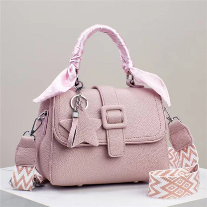 Pink handbag with a decorative strap on a light gray background