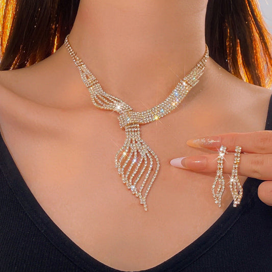 Gold-tone clavicle chain jewelry set with ribbon-like pendant and matching dangling earrings
