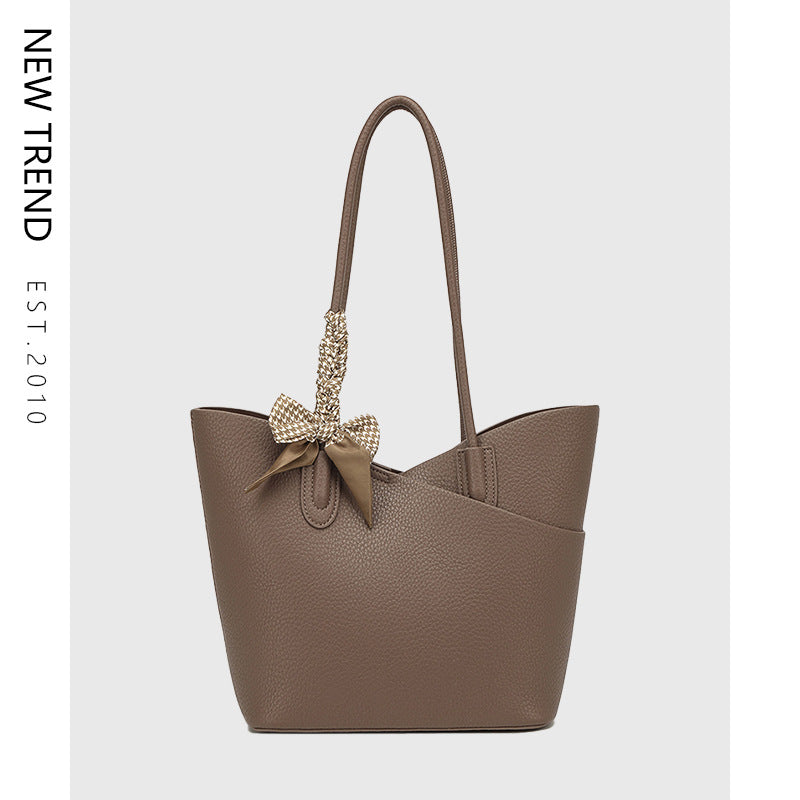 Brown handbag with a decorative bow on a light gray background