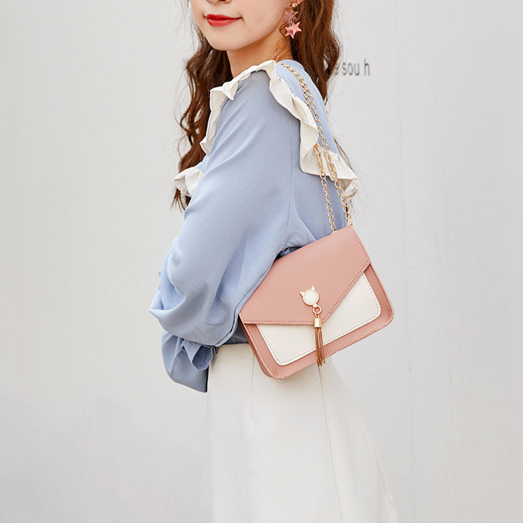Woman holding a pink and white handbag against a plain background