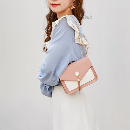 Woman holding a pink and white handbag against a plain background