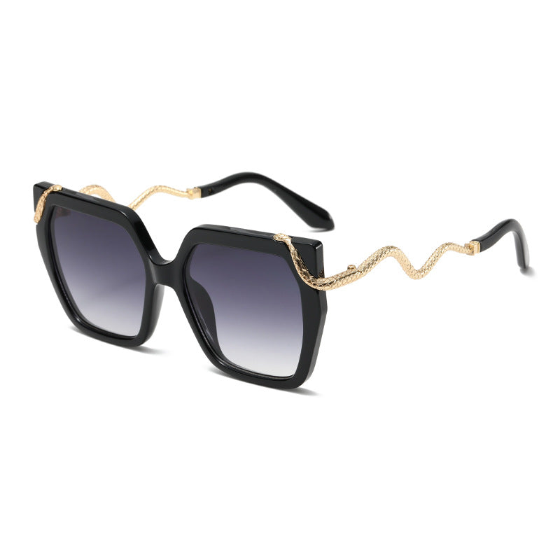 Black sunglasses with gold chain detail on a white background