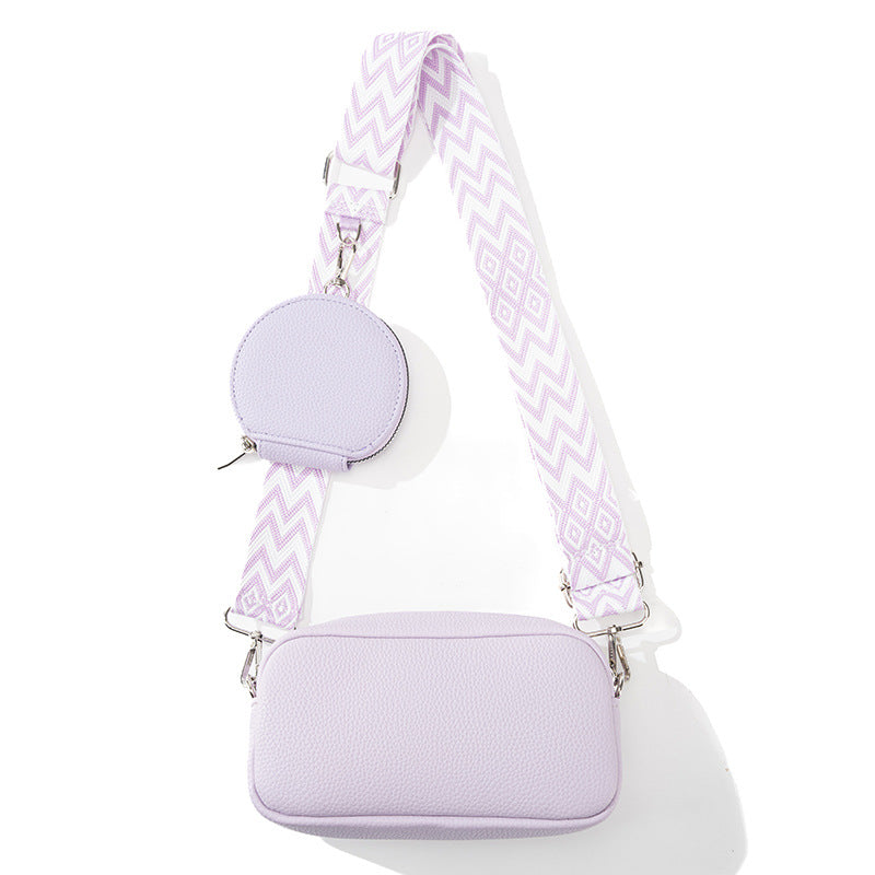 Lavender handbag with a matching round pouch and patterned strap on a white background