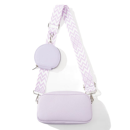 Lavender handbag with a matching round pouch and patterned strap on a white background