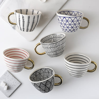 Set of six patterned mugs with gold handles on a white surface