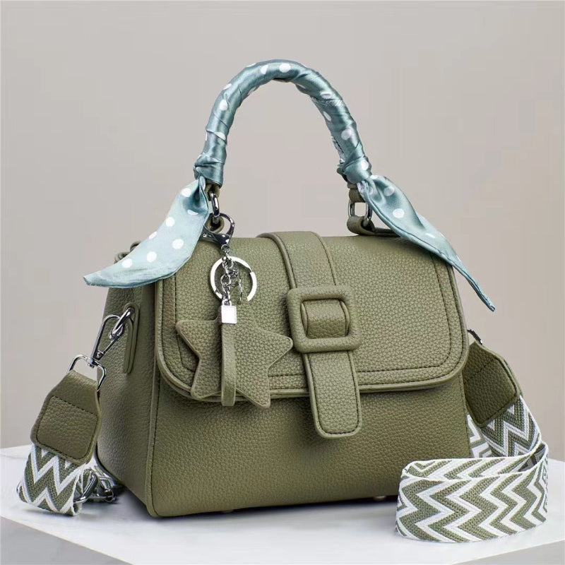 Green handbag with decorative handle and strap on a neutral background