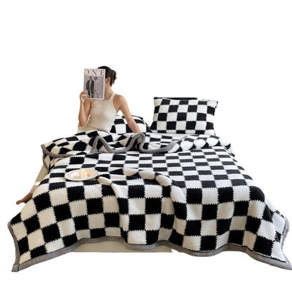 Person sitting on a bed with black and white checkered bedding
