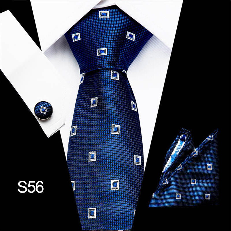 Blue patterned tie with matching pocket square and cufflinks on a white shirt.