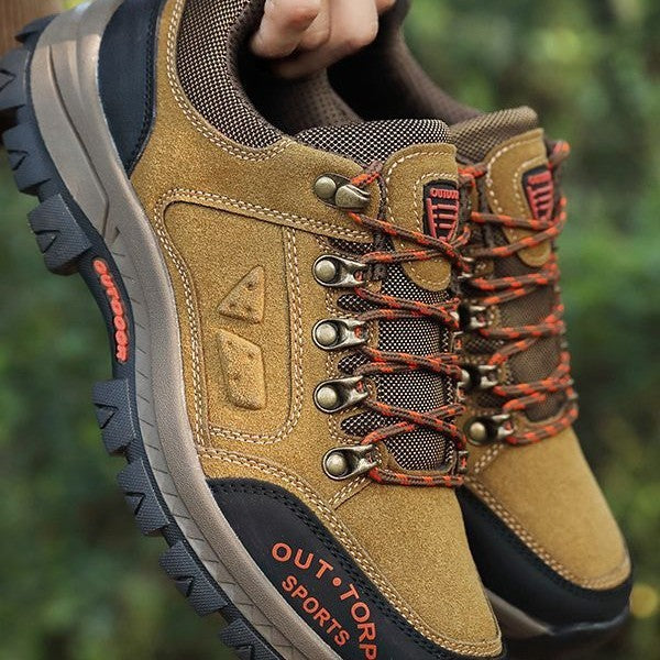 Brown outdoor shoes with orange accents and 'Outdoors' branding on a blurred green background