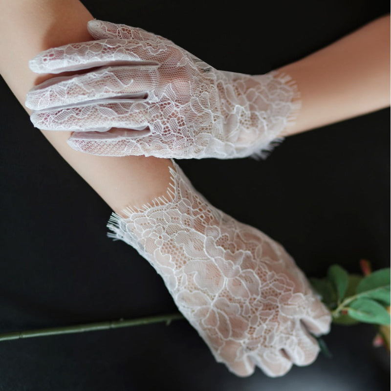 White lace gloves held by a person against a dark background