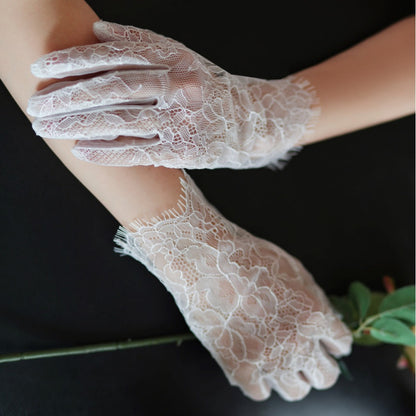 White lace gloves held by a person against a dark background