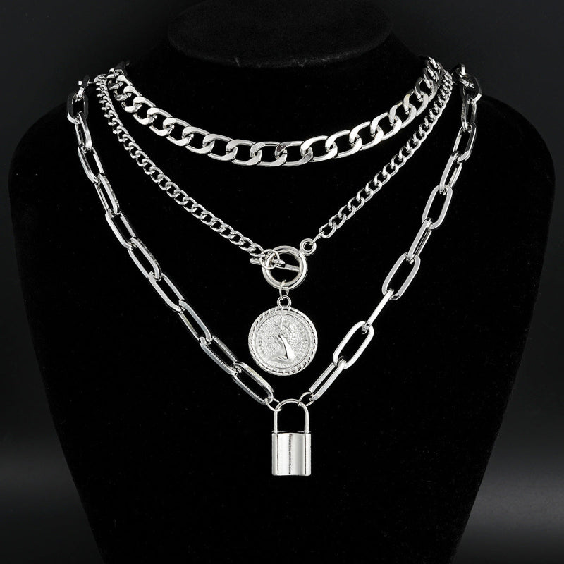Silver chain necklace with padlock and round pendant on a black stand
