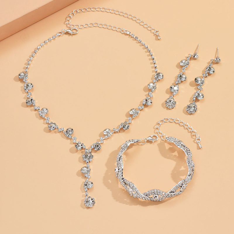 Silver jewelry set with necklace, bracelet, and earrings on a beige background