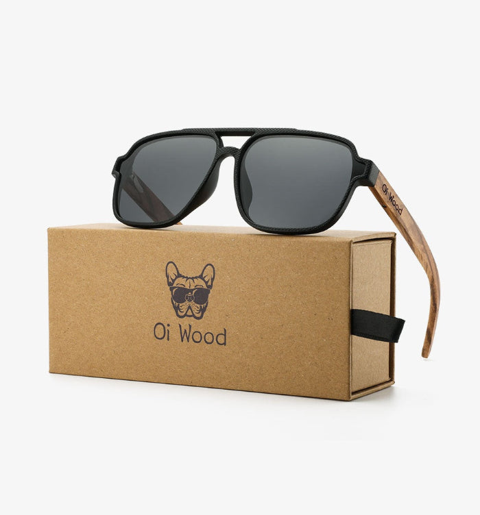 Black sunglasses with wooden arm on a cardboard box labeled 'Oi Wood' against a white background