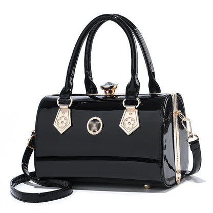 Black patent leather handbag with gold accents on a white background