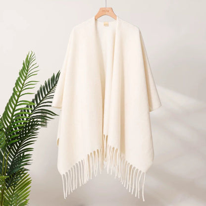 Cream-colored shawl with fringe on a wooden hanger against a light background