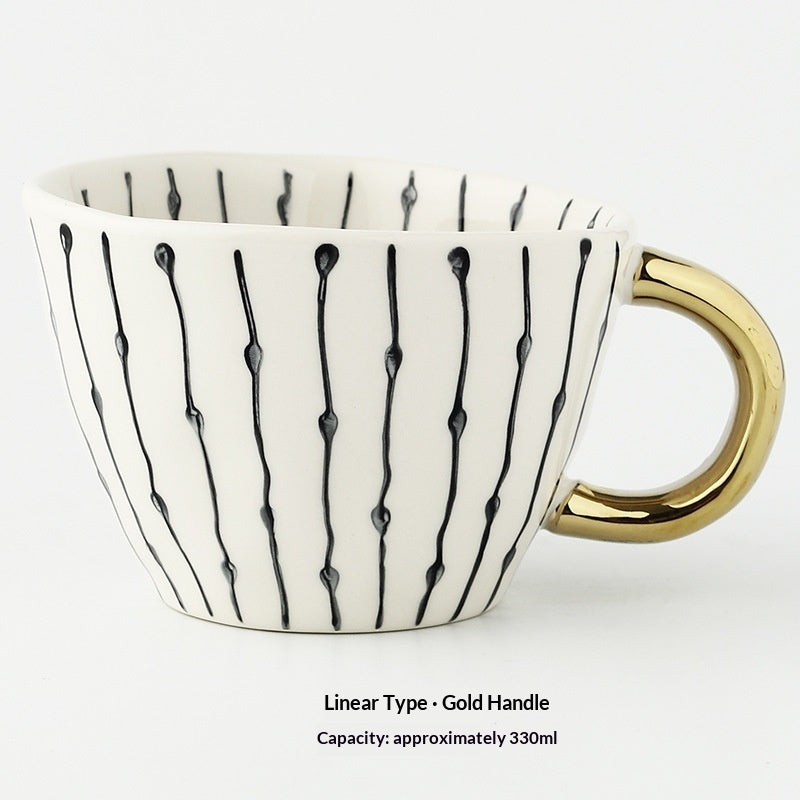 White mug with black abstract patterns and a gold handle on a white background
