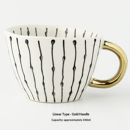 White mug with black abstract patterns and a gold handle on a white background