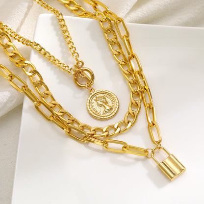 Gold chain necklaces with padlock and round pendant on a white surface
