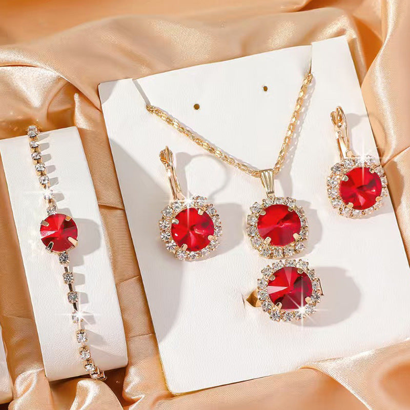 Jewelry set with red gemstones and gold accents on a satin surface