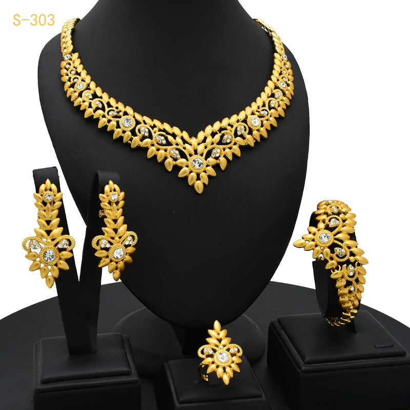 Gold jewelry set including necklace, earrings, and bracelet on a black stand.