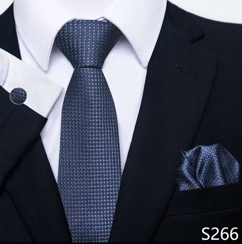 Black suit with white shirt, blue patterned tie, and matching pocket square on a white background.