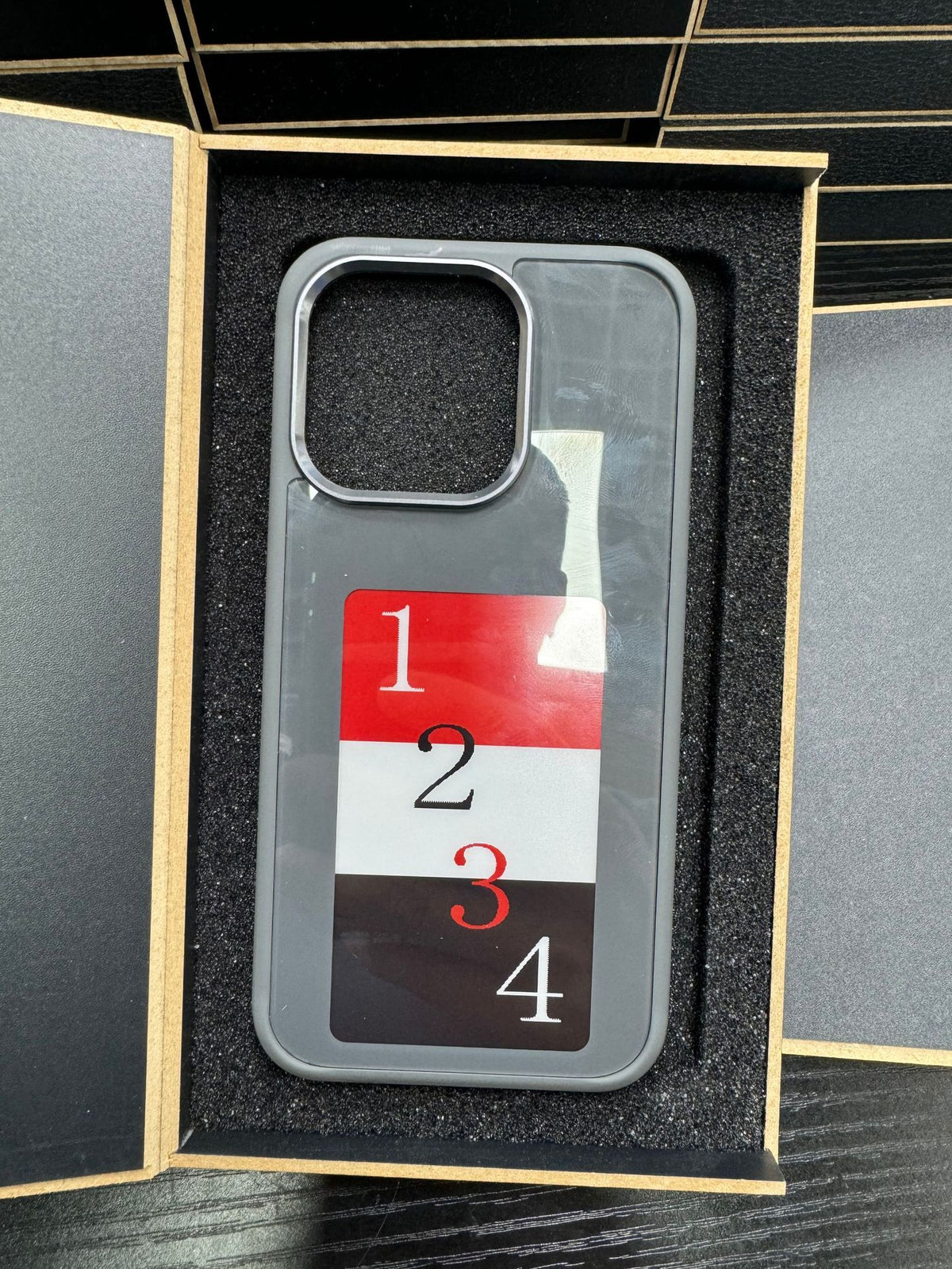 E-ink smart display phone case in box, dark back with numbered e-ink display