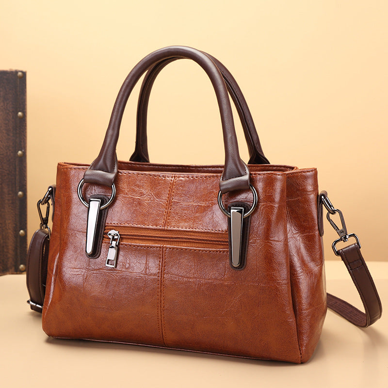 Brown large-capacity handbag with front zipper panel, two top handles, and crossbody strap