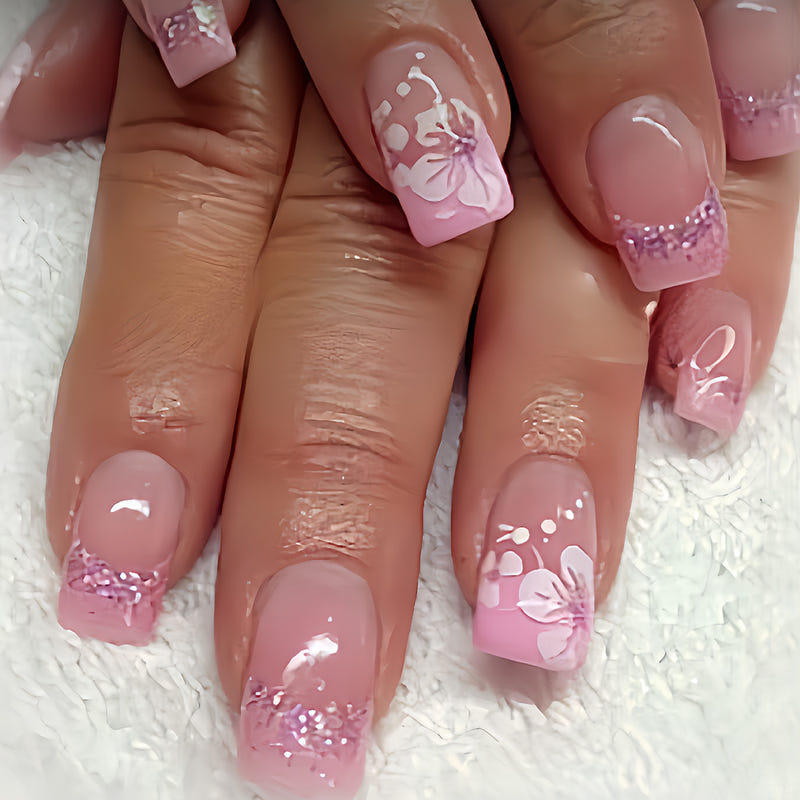 Close-up of pink translucent press-on nails with French tips and white floral bow decals