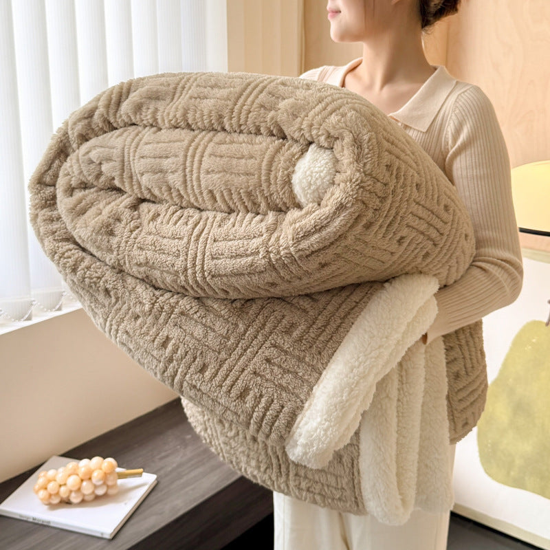 Person holding a large beige knitted blanket indoors.