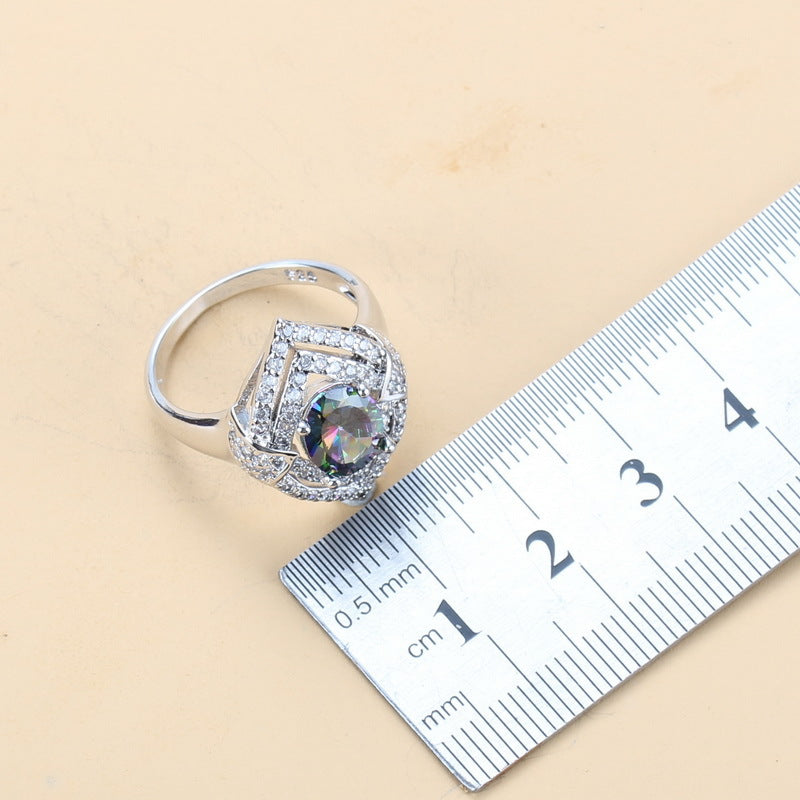 Silver ring with a large gemstone next to a ruler on a beige background