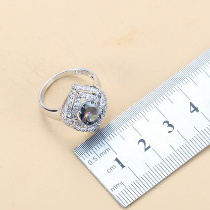 Silver ring with a large gemstone next to a ruler on a beige background