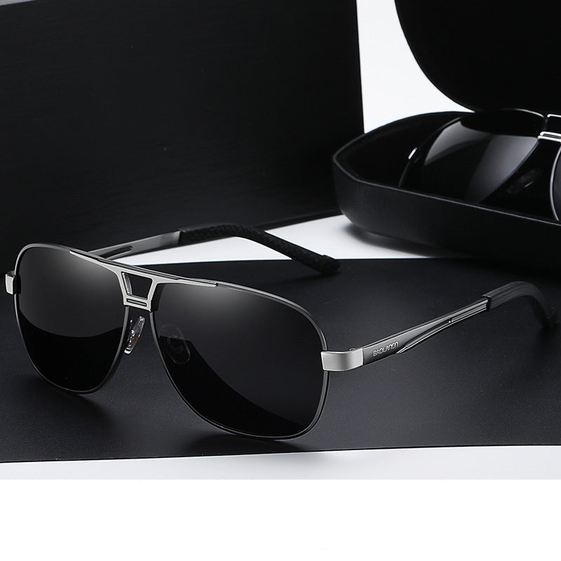 Sunglasses with gunmetal frame and gray lenses on a black surface.