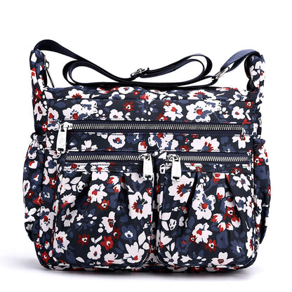 Navy floral crossbody bag with adjustable strap and several zip compartments