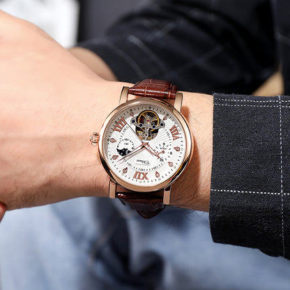 Luxury watch with brown leather strap on a person's wrist, wearing a suit.