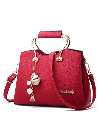 Red handbag with gold accents and a decorative charm on a white background