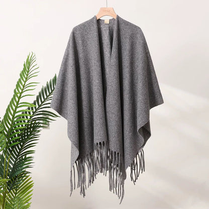 Gray poncho with fringe on a hanger against a white background