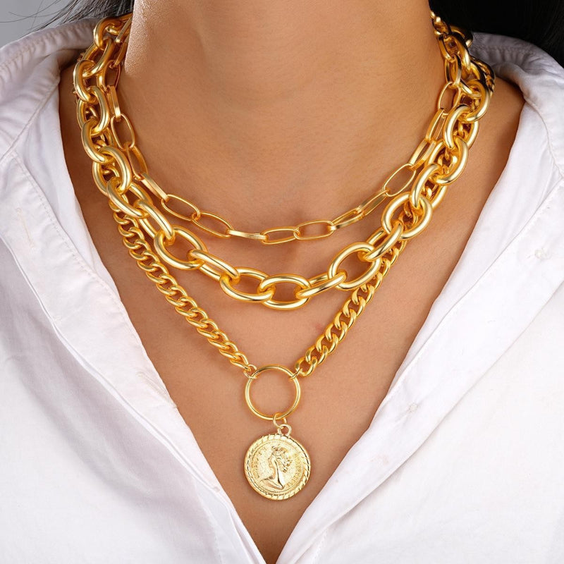 Gold chain necklaces with a pendant on a white shirt background