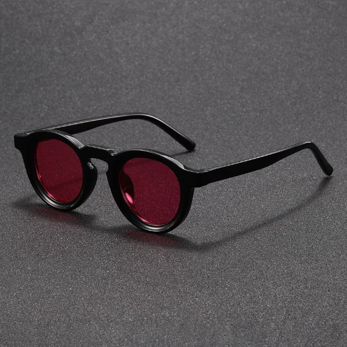 Black sunglasses with red lenses on a gray background