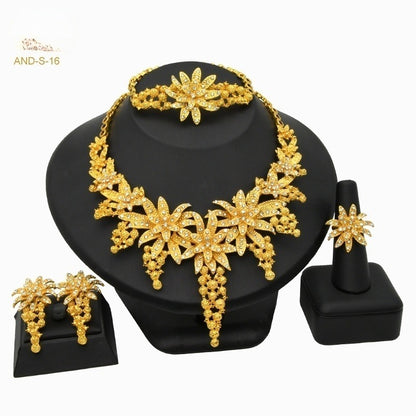 Gold jewelry set including necklace, bracelet, earrings, and ring on a black stand with 'AND-S-16' branding.