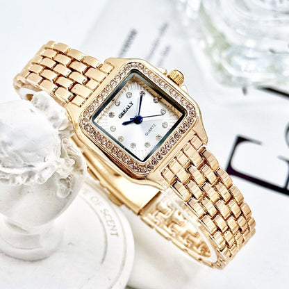 Gold wristwatch with a decorative band on a white background