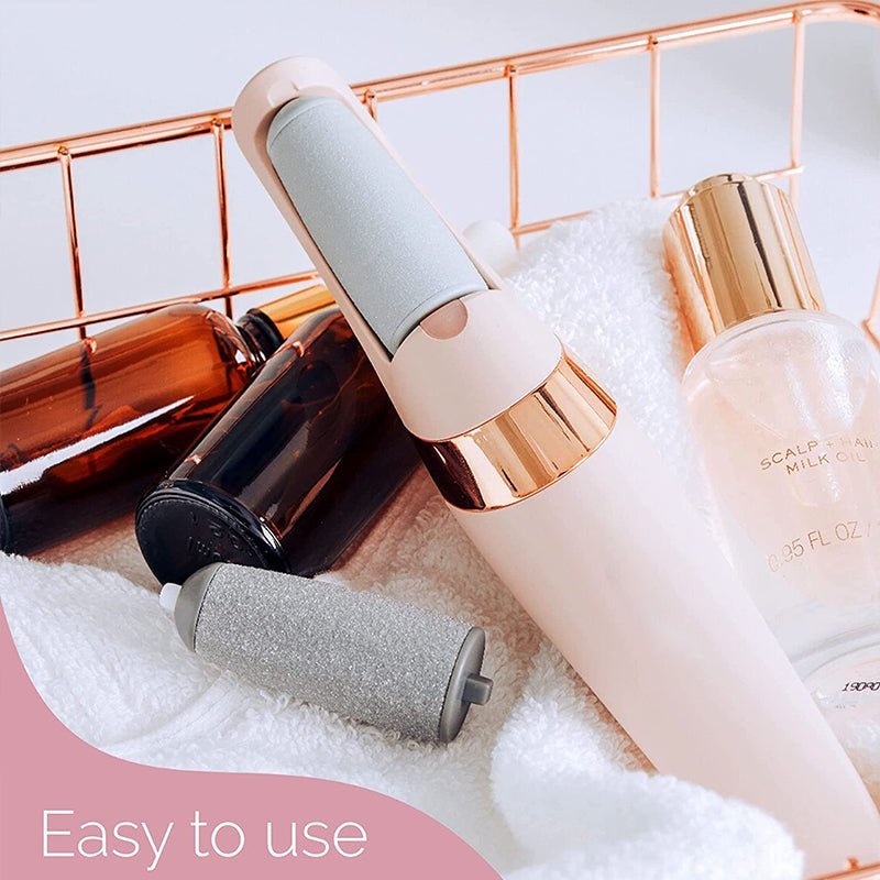 Pink rechargeable electric foot file and spare roller resting on a folded towel