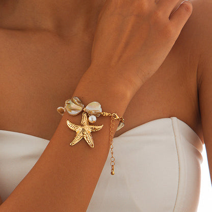 Women's Gold bracelet with starfish and shell charms on a wrist against a neutral background